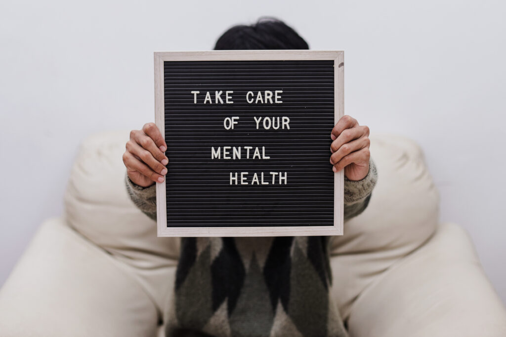 man holding up a take care of your mental health sign