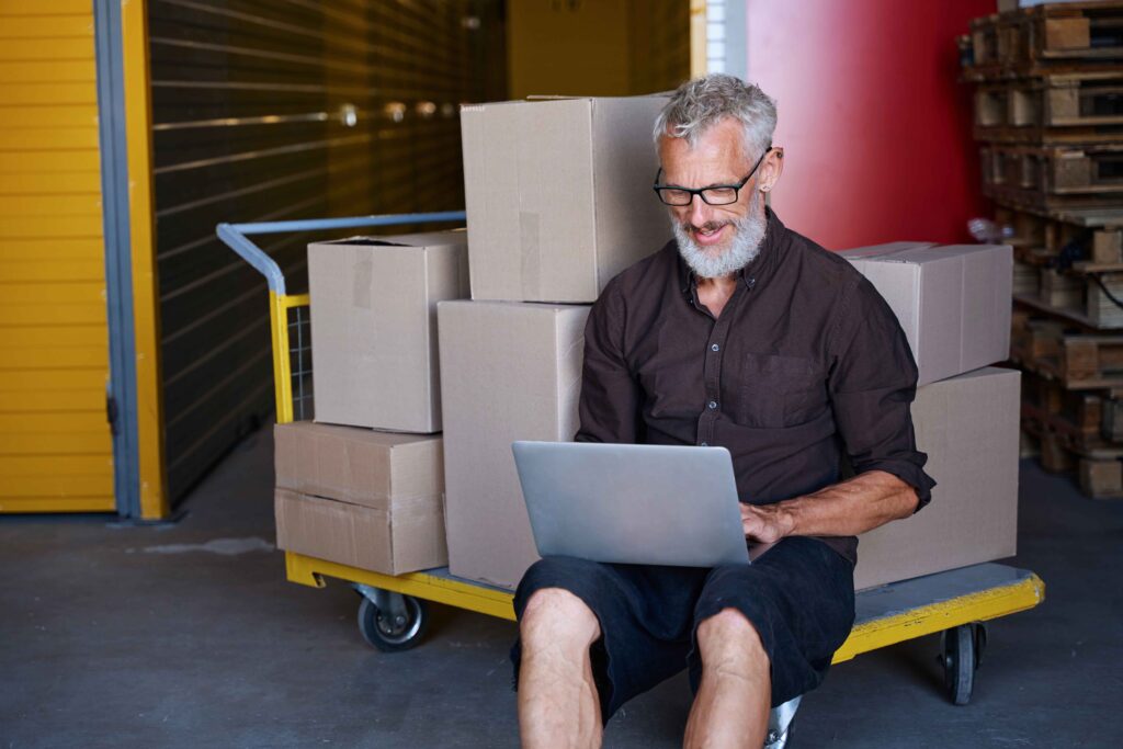 man over 50 with boxes of goods he has sold from his e-commerce website